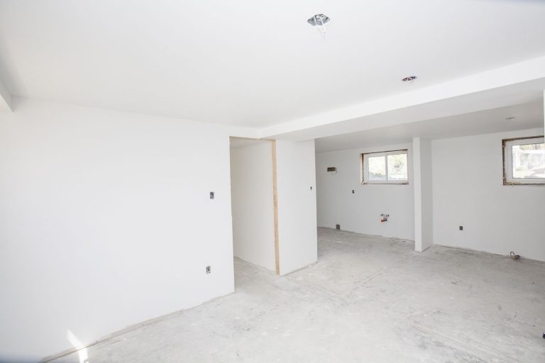 A white unfinished basement with recessed lighting and windows, Why Is My Basement Ceiling Cracking?