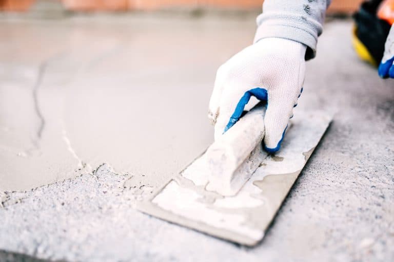 A worker spreading waterproofing on the concrete floor, Can You Drylok A Basement Floor?
