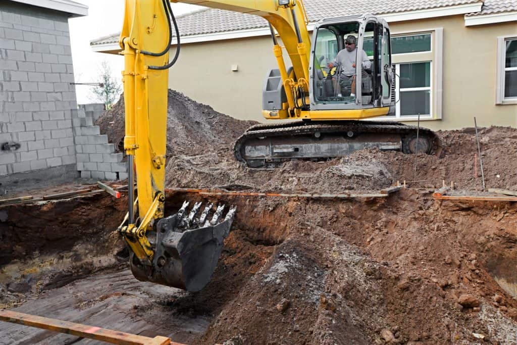 An excavator taking off dirt for a proposed residential building