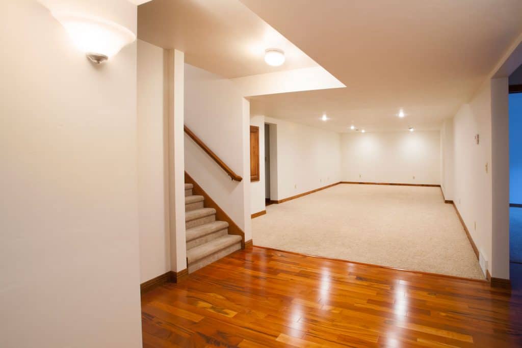 Interior of a wooden flooring basement and a small carpeted area for the guest bedroom