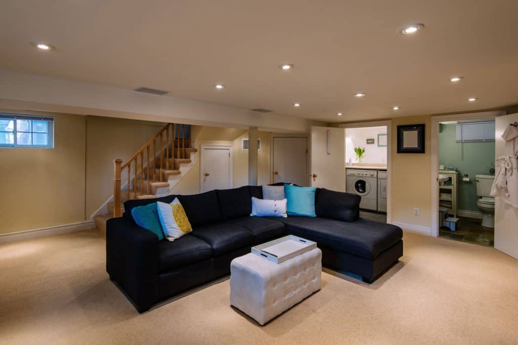Modern basement with carpeted flooring recessed lighting and black sectional sofa