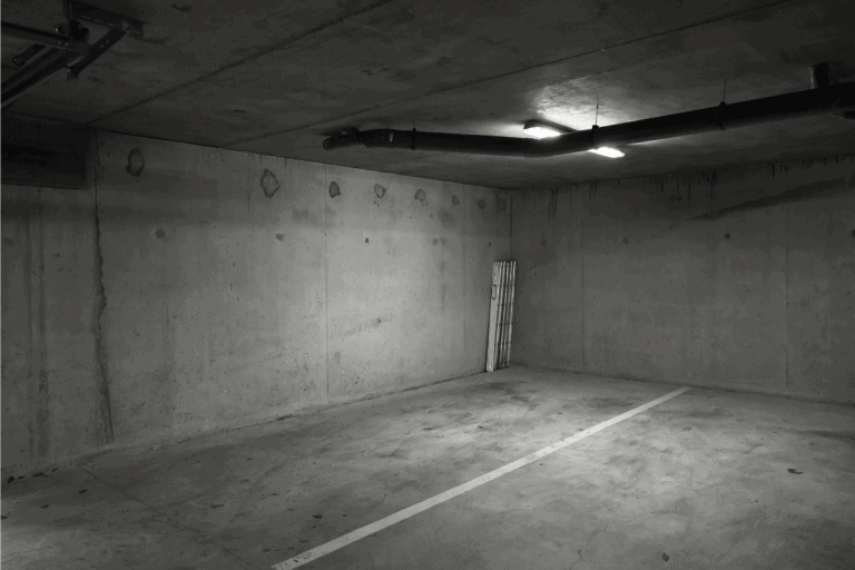 Abstract empty basement parking lot interior with dark gray concrete walls and white ceiling lights