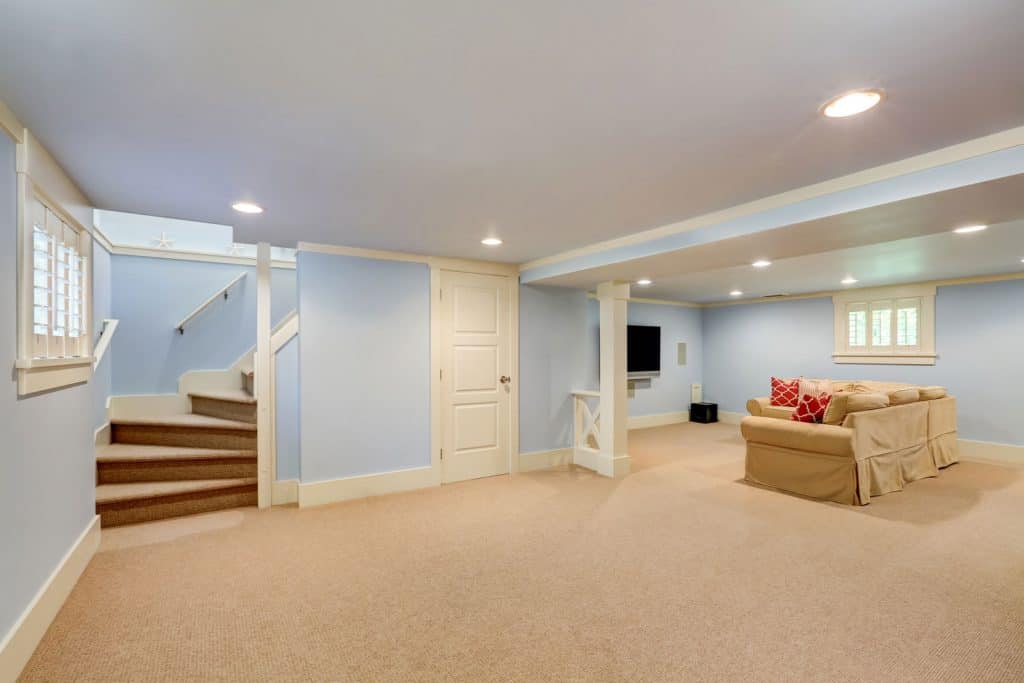 Elegant and bright interior of basement with carpeted flooring, blue walls, recessed lighting and a small entertainment area, Should A Basement Door Be Opened Or Closed In The Summer?