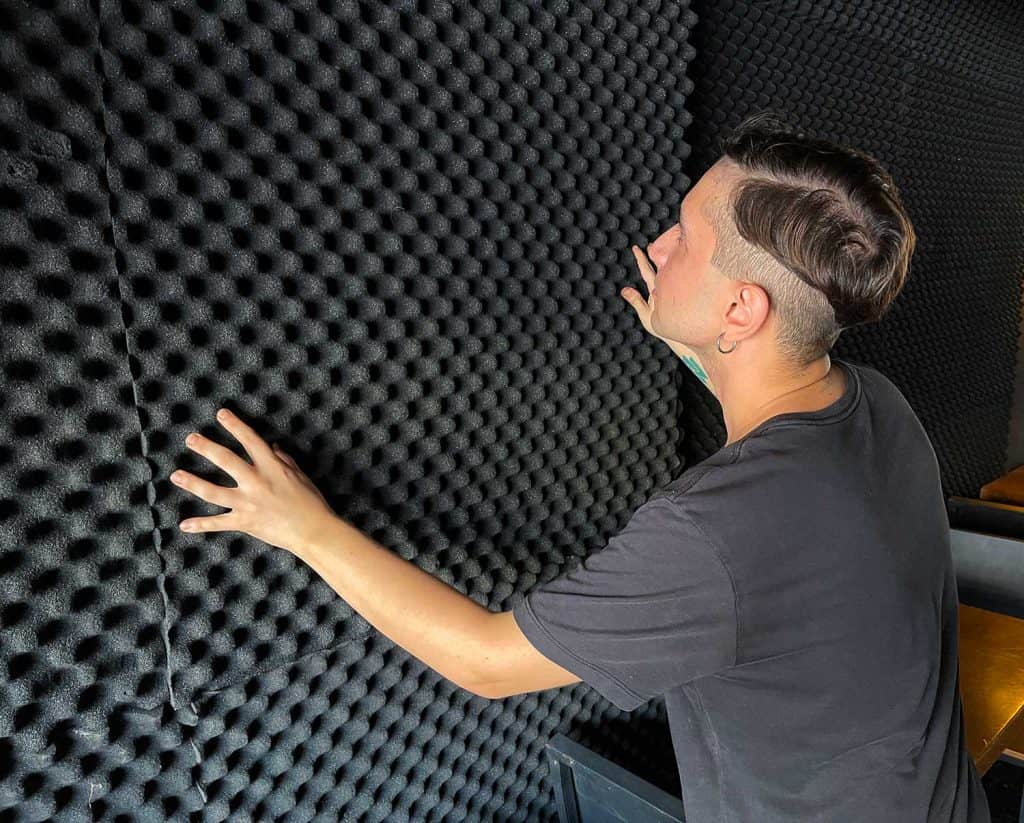 Man soundproofing a wall with acoustic foam