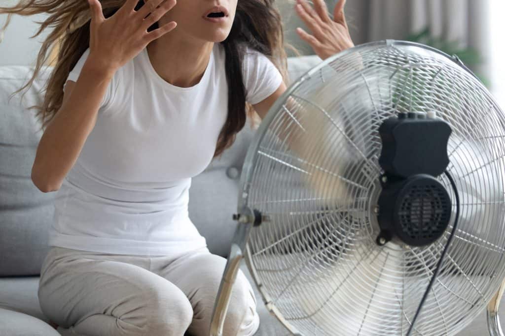 Woman turned on fan waving her hands to cool herself