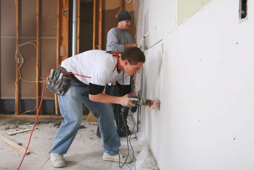 A worker installing a drywall using rivets