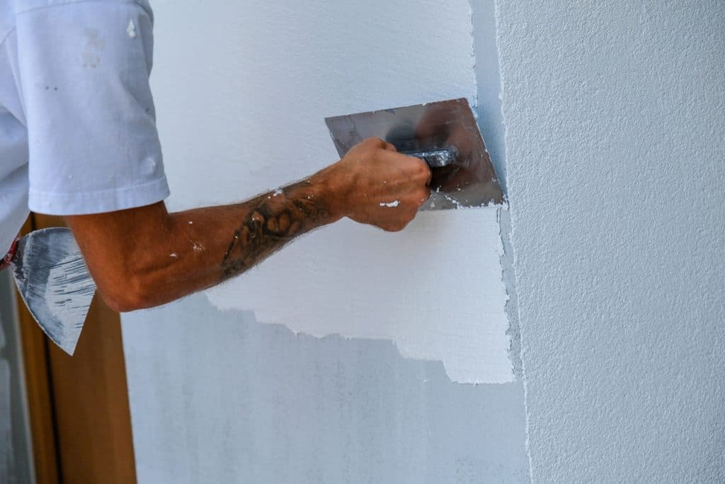 A man applying primer into the unpainted wall