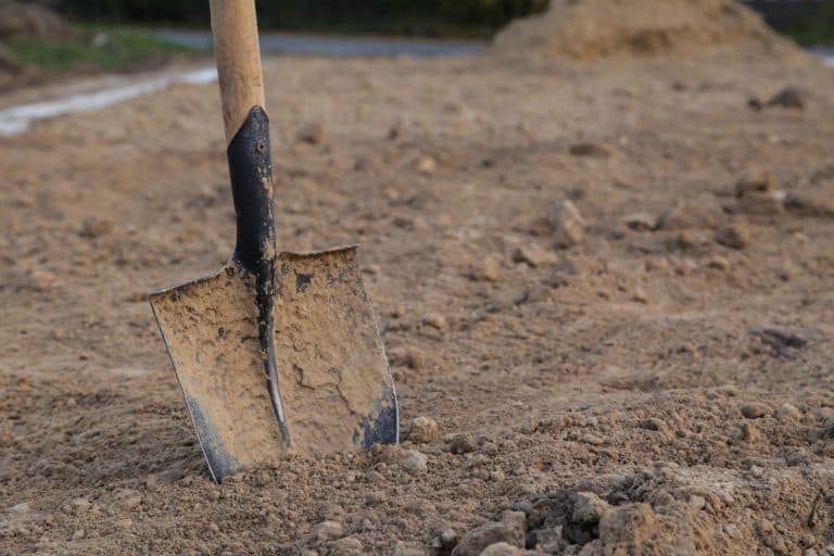 Dirty closeup spade in dry clay soil, basement construction, Can You Build A Basement In Clay Soil?