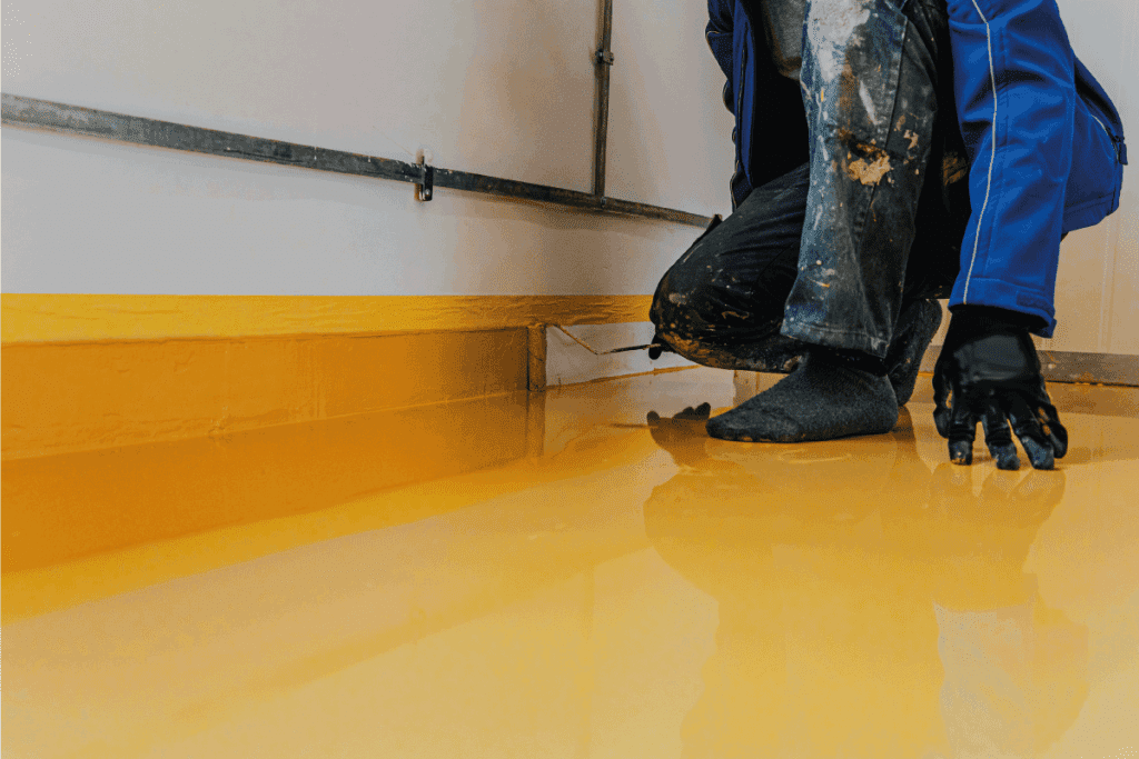 Worker, coating floor with self-leveling epoxy resin. finishing touches. Can You Epoxy A Basement Floor