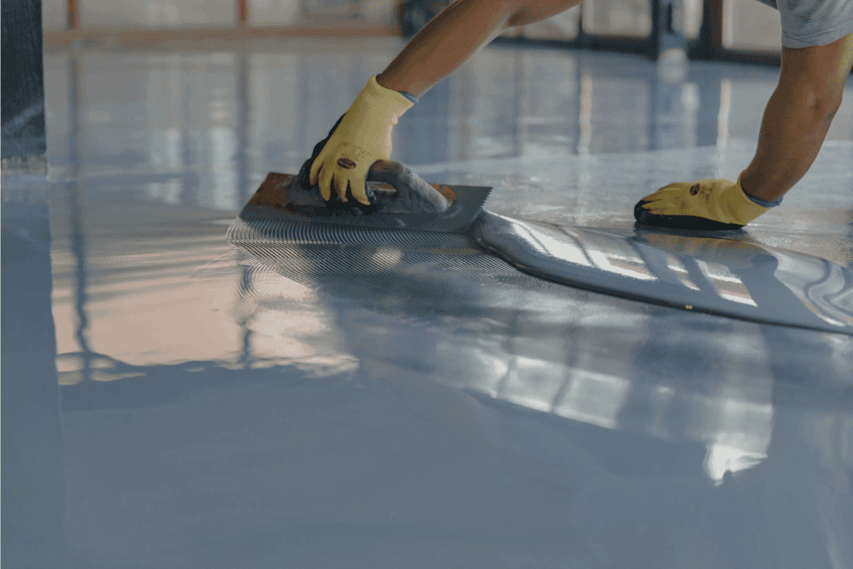A worker applying epoxy on a floor