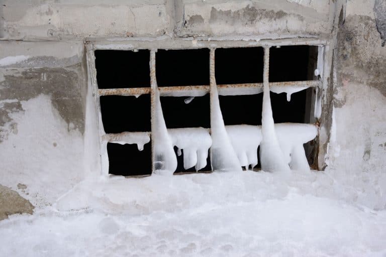 Basement with grill of rusty iron covered with ice, How To Protect Basement Windows From Snow