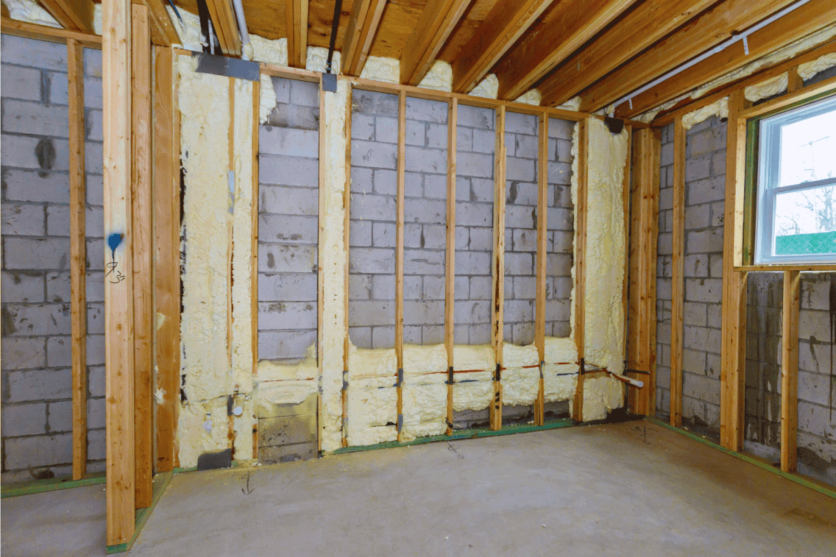 New wooden house in foam for insulation the wall of a basement unfinished under construction, ceiling joist showing
