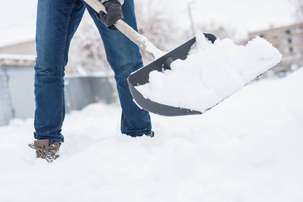 close-up-view-of-snow-shovel-with-snow-in-mans-hands.-Man-clean-backyard-of-his-house-after-blizzard.-Spring-snow-cleaning.