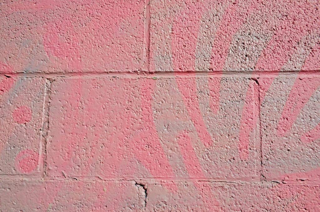 A textured background of cinder blocks painted pink and grey