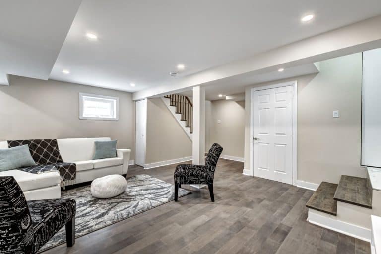 Modern contemporary inspired basement with vinyl flooring, white ceiling with recessed lighting and large sofas, How Wide Should A Basement Door Be