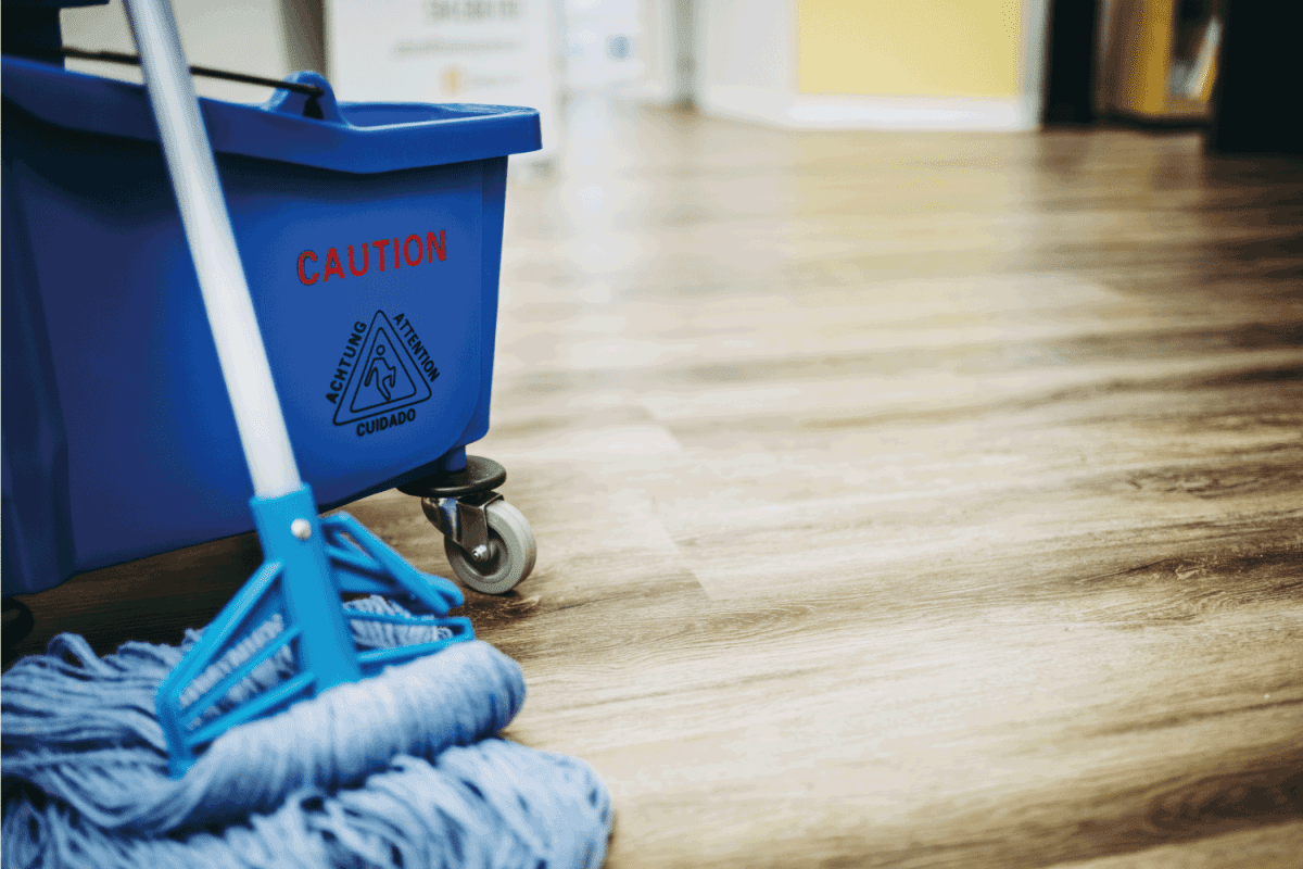 Mop bucket on wood floor. Caution wet floor