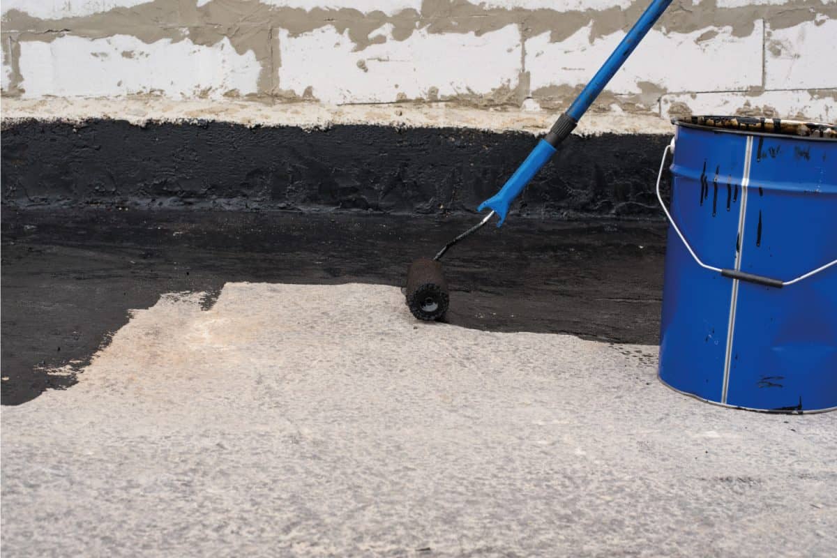 .Roller brush. Worker covered surface, bitumen primer for improving adhesion during surfacing, rolled waterproofing