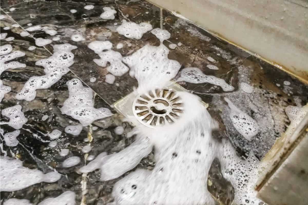 Soap foam suds and water flowing into bathroom drainage hole