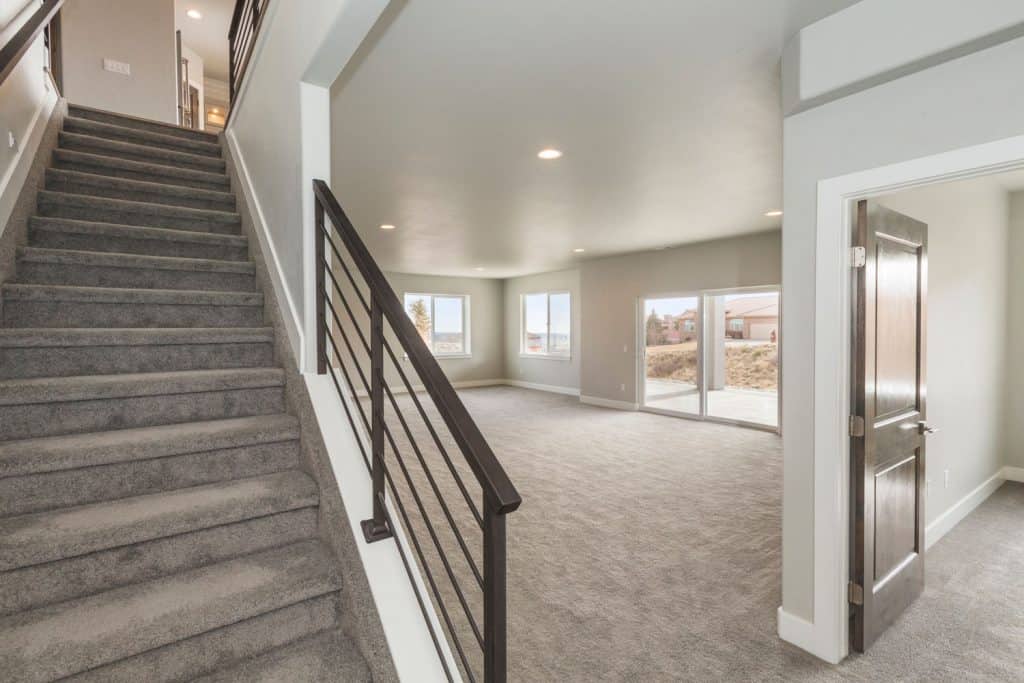 a luxurious walkout basement with wide-angle view showing the stairs leading up
