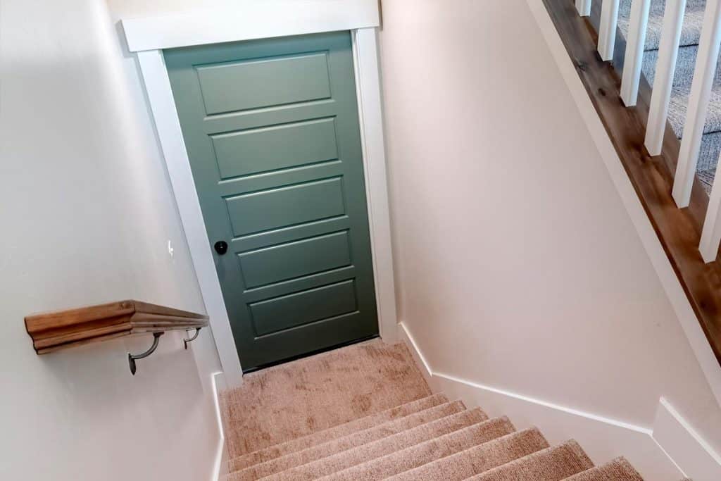 Stairs of home with carpeted treads that leads down to the basement door, Do Basement Doors Need Headers?