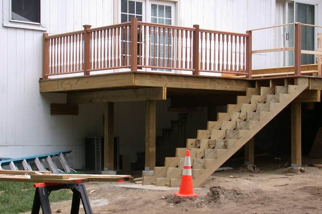 Unfinished stairs outside a two story white siding house