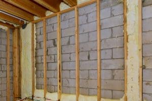 Wooden framing of a basement with unfinished insulation and the floor joist above, How To Frame A Basement Wall Parallel To Floor Joists