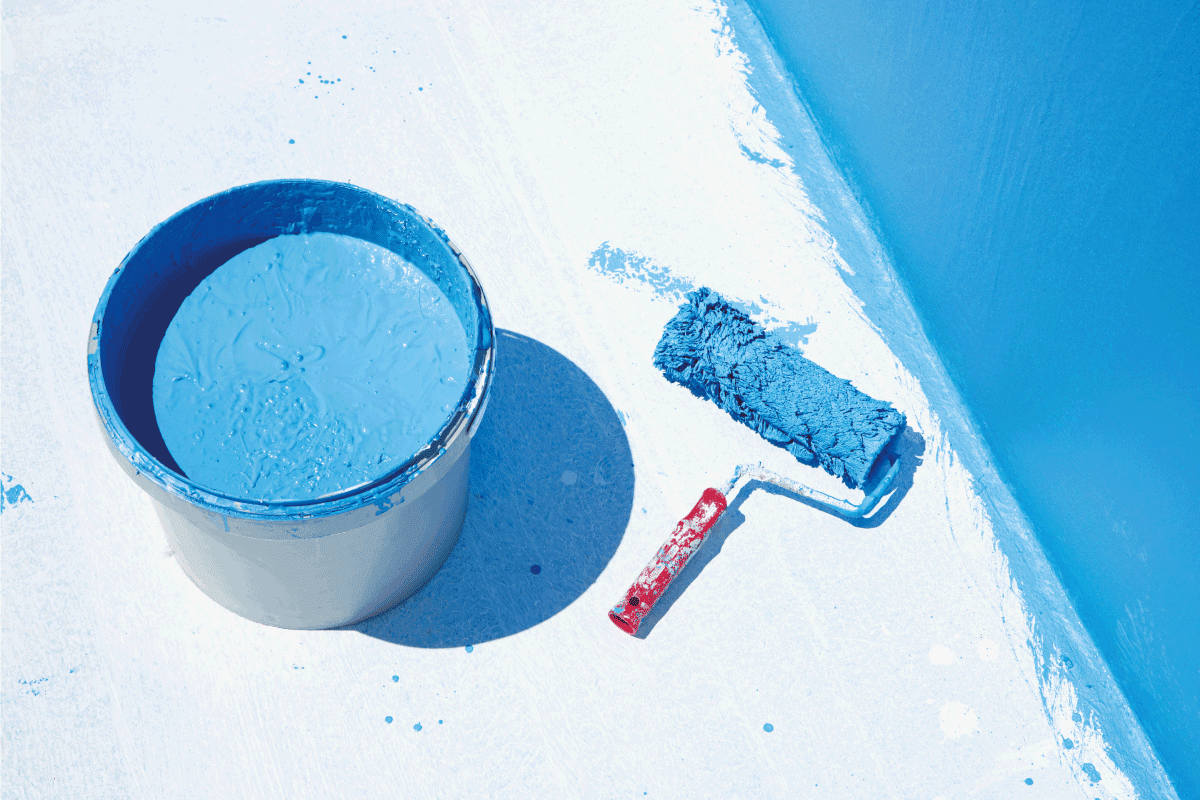 blue waterproofing paint on a concrete floor with paint roller on the side. Can You Paint Over Drylok