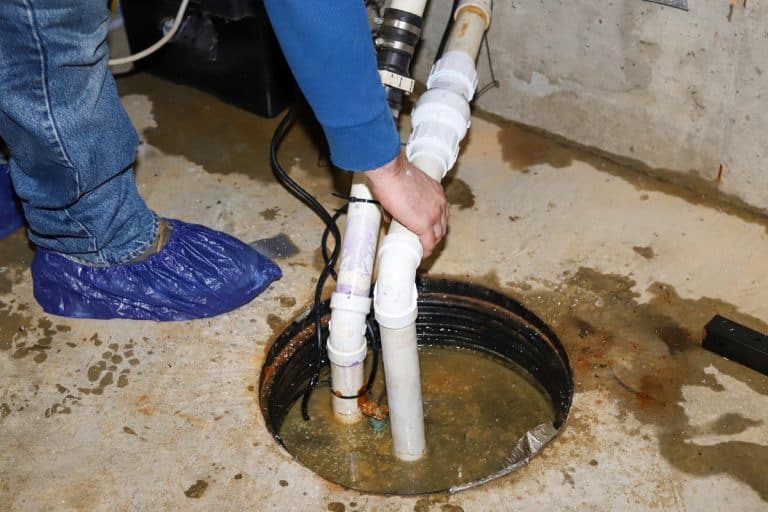 A plumber repairing a sump pump in a flooded basement, Clogged Sump Pump: How To Fix It