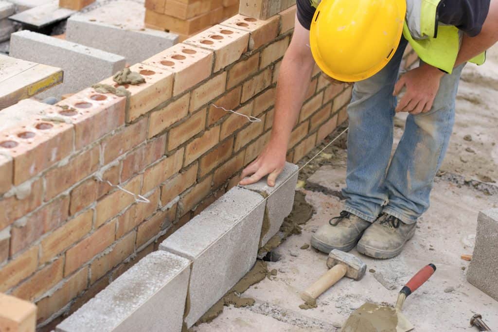 Construction worker laying cinder blocks for the basement wall