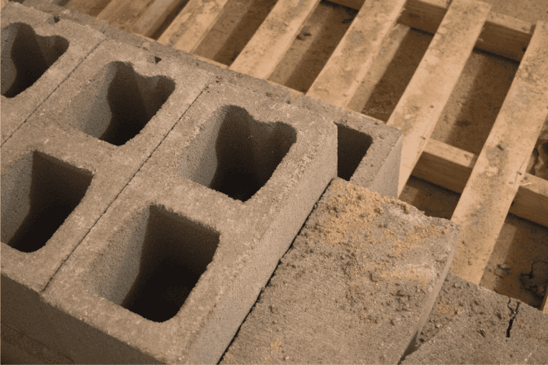 Solid and hollow concrete blocks stacked on a wooden pallet. How To Remove Cinder Block From Basement Wall [Single Block And Rows Of Blocks]
