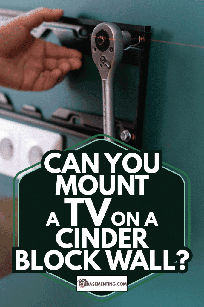 worker using ratchet to install tv wall mount. Can You Mount A TV On A Cinder Block Wall