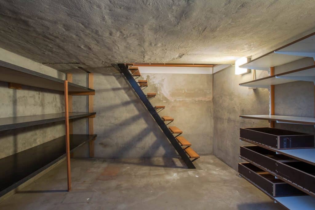 Interior of an empty basement with wooden shelves and wooden stairs