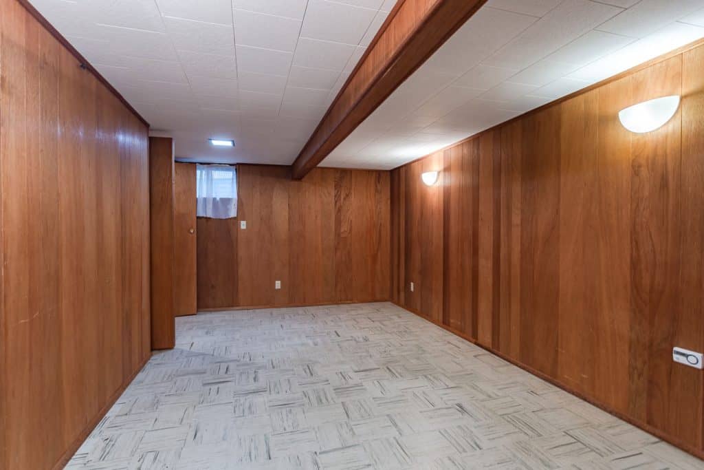 Wooden paneled basement walls and white black and white marble tiles