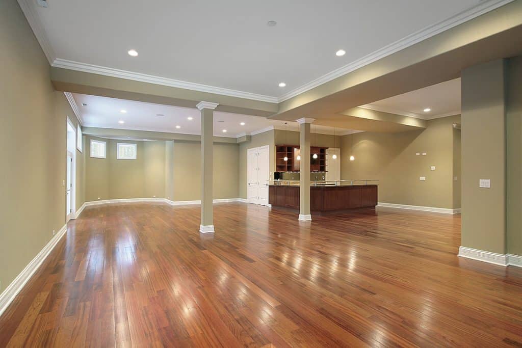 A hardwood flooring basement with green painted walls and white painted trims